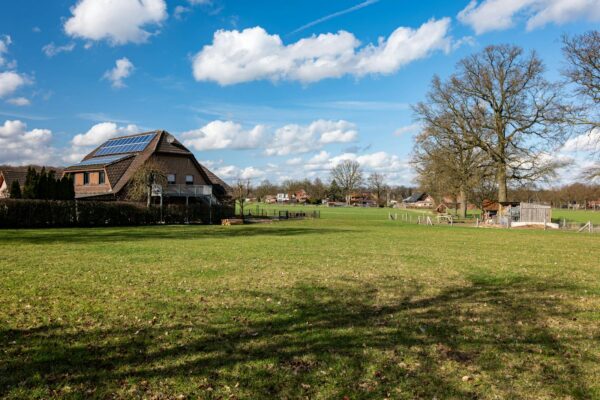 Laendliches Haus mit Solaranlage und Wiese als Symbolbild fuer Grundstuecke in Bayern
