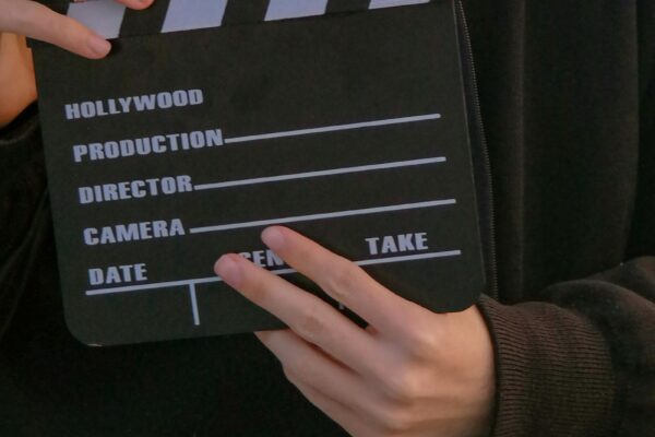 Mann mit Filmklappe als Symbolbild fuer Hochschule fuer Film und Fernsehen Muenchen