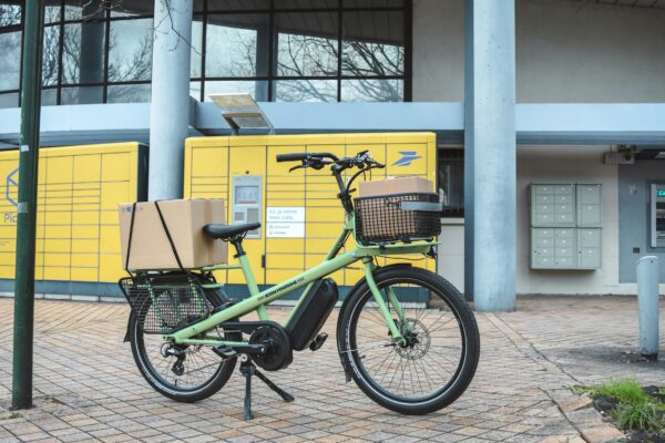 Elektrisches Lastenrad mit Paketen vor Postschließfächern - Klimafreundliche Lieferung im Handwerk