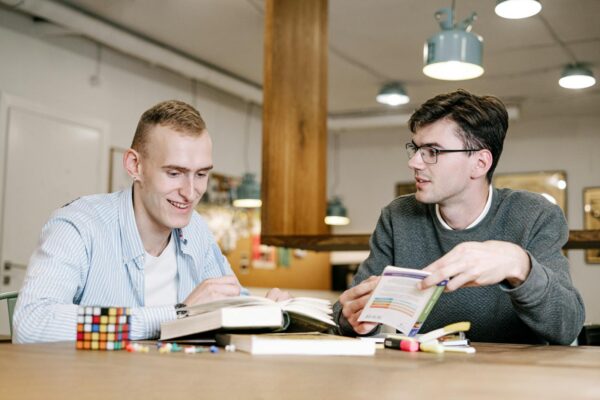 Zwei Studierende lesen Buecher in einer Bibliothek