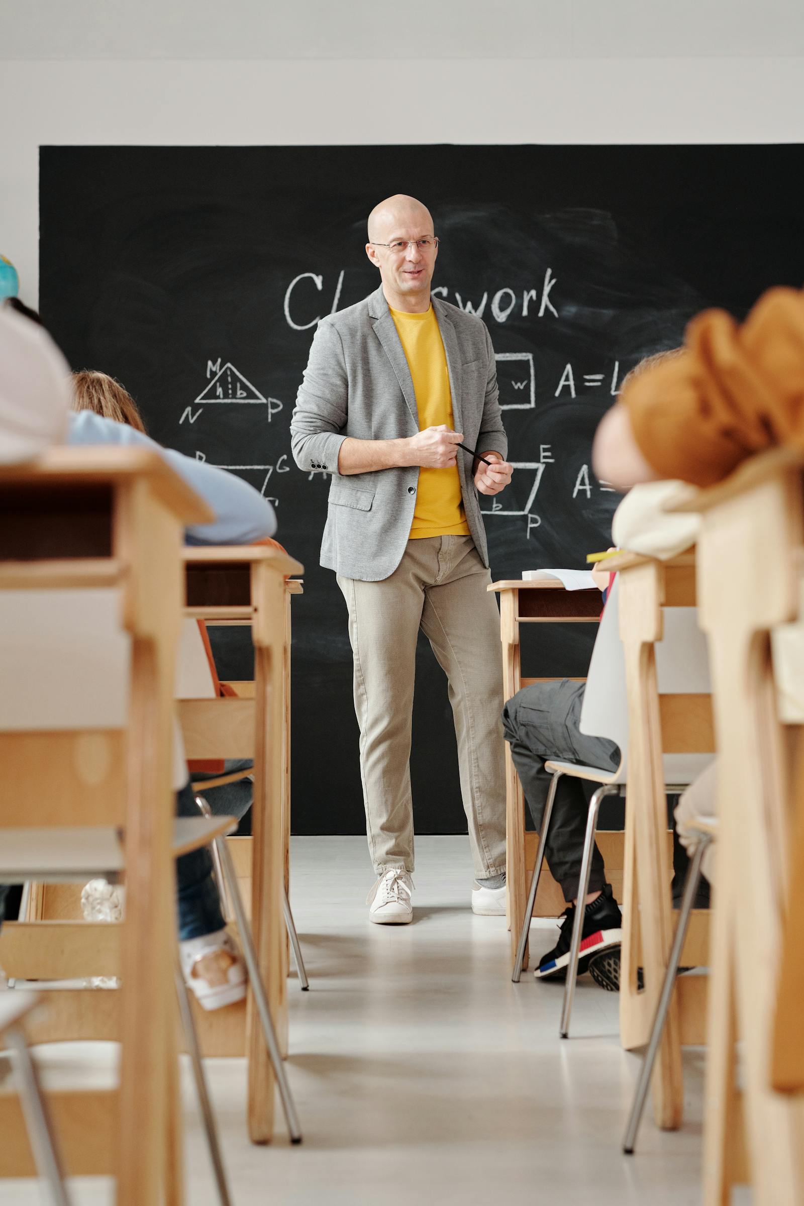 Lehrer vor einer Tafel im Klassenzimmer als Symbolbild fuer dienstliche Beurteilung Lehrer Bayern